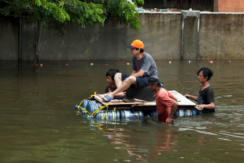 Men maneuvering a makeshift raft through floodwaters in Jakarta, showcasing resilience.