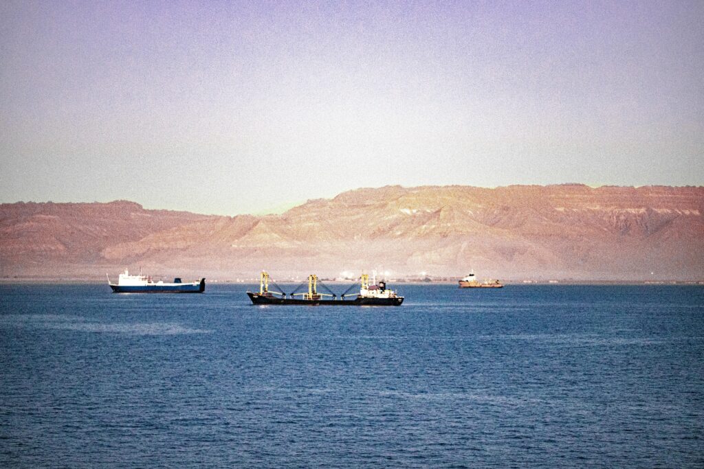 Serene view of cargo ships navigating the Suez Canal with mountains in the background.