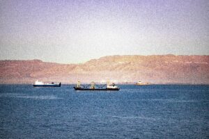 Serene view of cargo ships navigating the Suez Canal with mountains in the background.