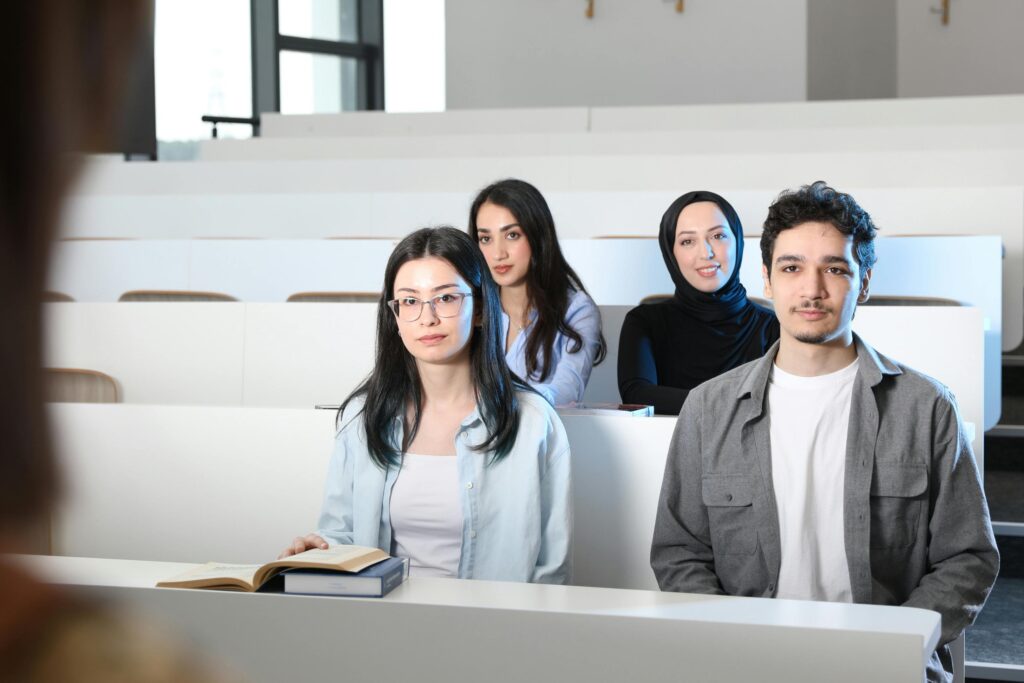 Group of diverse university students attending a class session in a modern lecture hall.