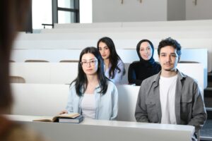 Group of diverse university students attending a class session in a modern lecture hall.