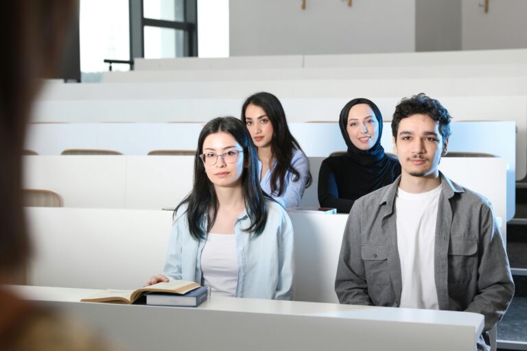 Group of diverse university students attending a class session in a modern lecture hall.