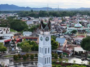 Aerial view of the historic Jam Gadang clock tower amidst Bukittinggi's vibrant cityscape in West Sumatra, Indonesia.