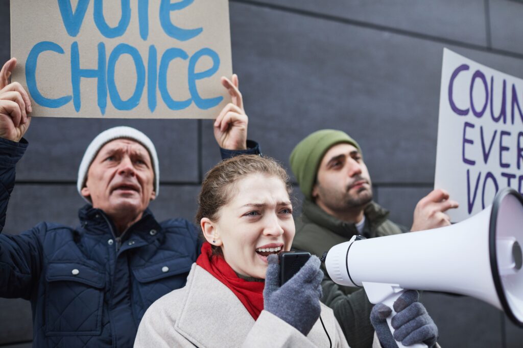 Protestors speaking out with signs and megaphone advocating for voting rights.