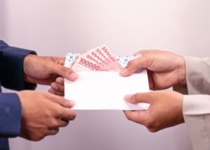 Hands exchanging an envelope with Indonesian Rupiah, highlighting financial transactions.