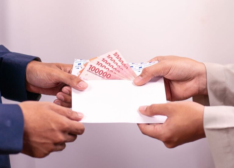 Hands exchanging an envelope with Indonesian Rupiah, highlighting financial transactions.